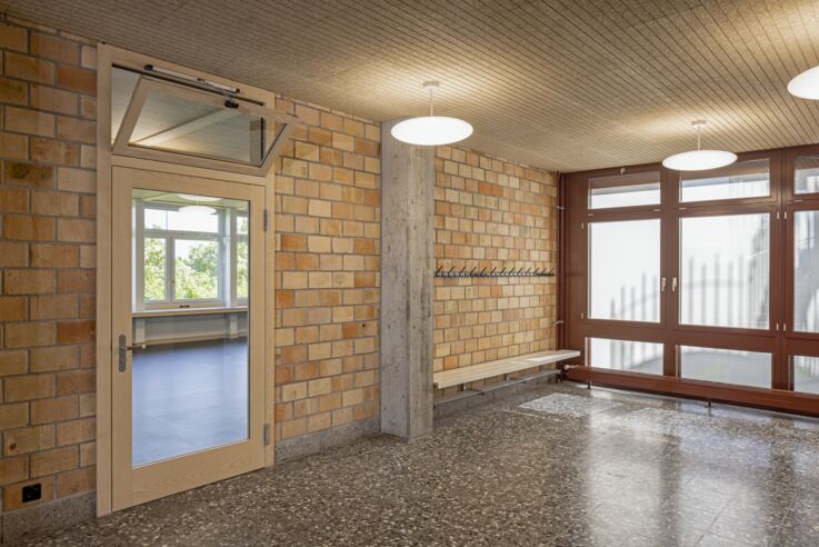 View of the school corridor with a glass door, the upper window of which is tilted open.