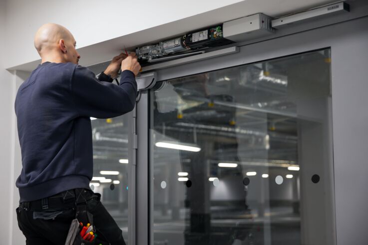 GEZE Service 的服务技术人员正在为一扇大型玻璃门安装闭门器